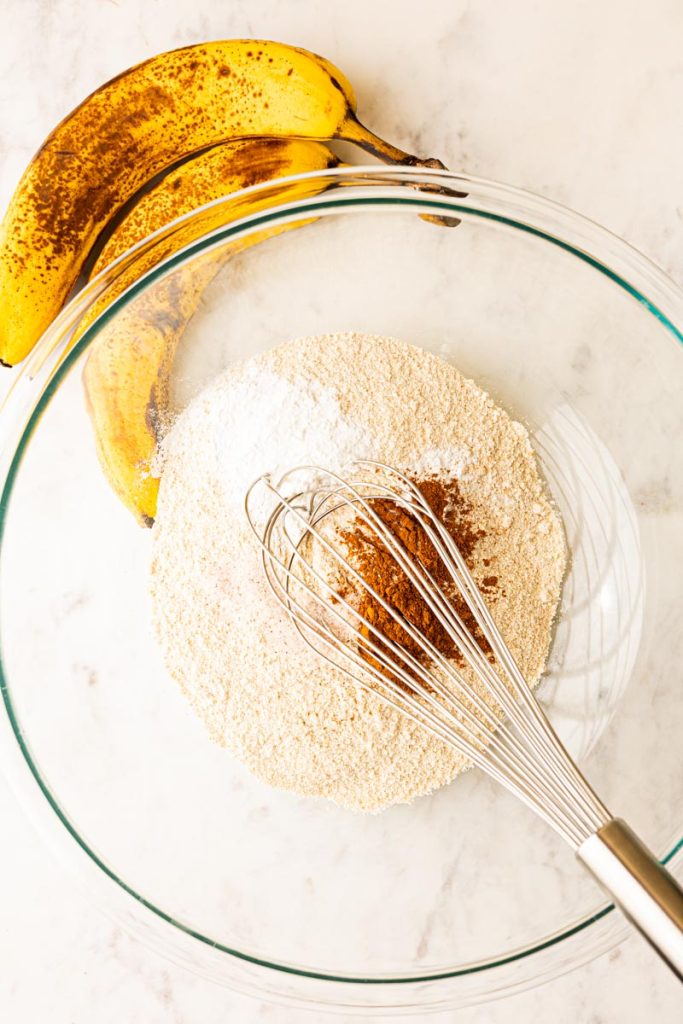 Banana bread dry ingredients in a glass mixing bowl with a whisk.