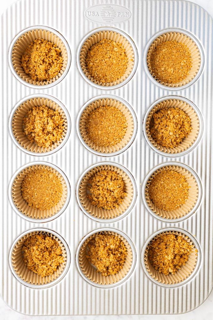 Graham cracker crust for mini cheesecakes, inside muffin liners in a baking pan.