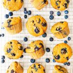 Blueberry lemon muffins on a cooling rack with fresh blueberries scattered around the muffins.